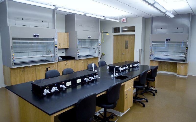 Laboratory classroom with bright, linear lights above a long table, chairs and lab equipment.
