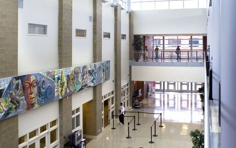 The entrance of Kennedy King College, showing some wall art and four students walking.