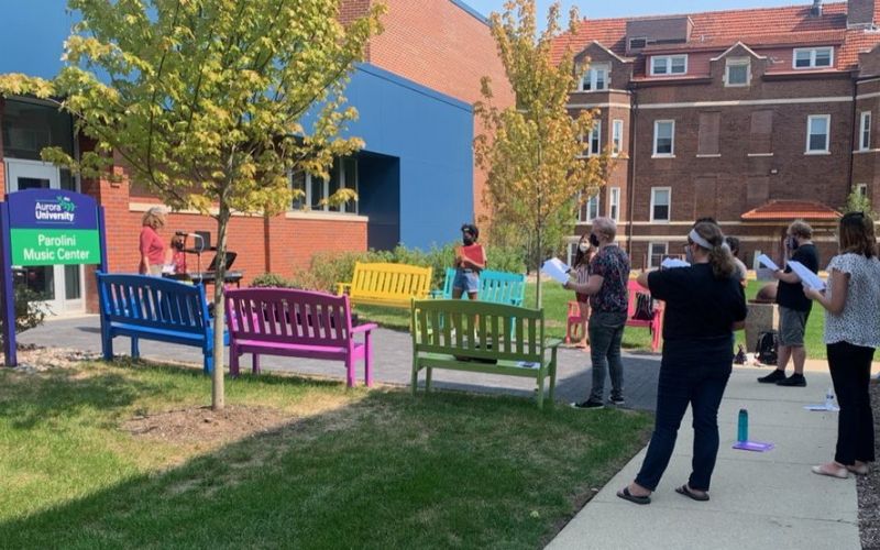 People standing outside the entrance to the Parolini Music Center, decorated with colorful benches.