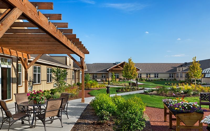 A covered patio at Silverado with a green, luscious garden and flowers.