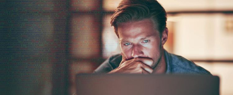 A man sitting at a laptop in contemplation