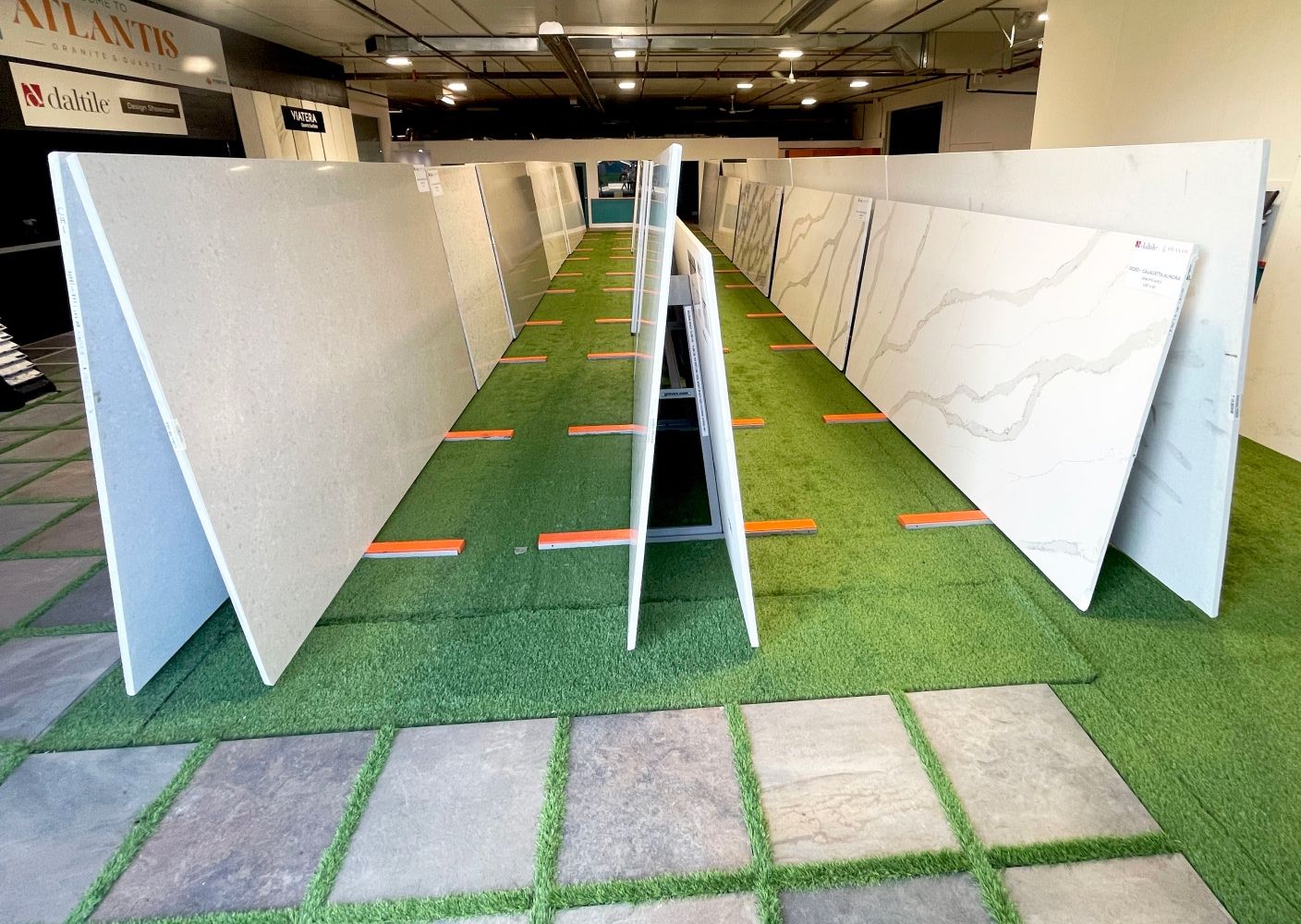 Hallways made of Stone Slabs in Atlantis Granite and Quartz Showroom with green faux grass