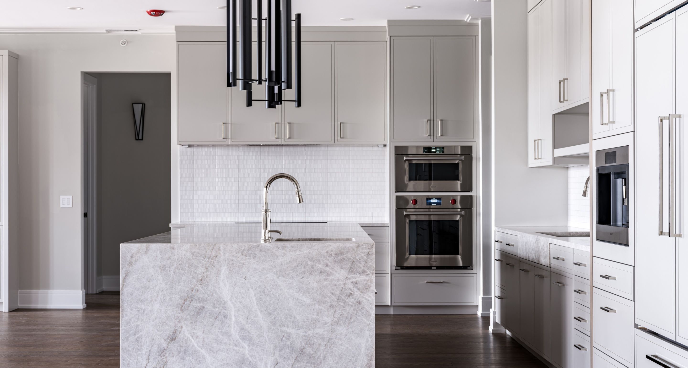 Kitchen with stone countertops and island, white cabinets, and white sink
