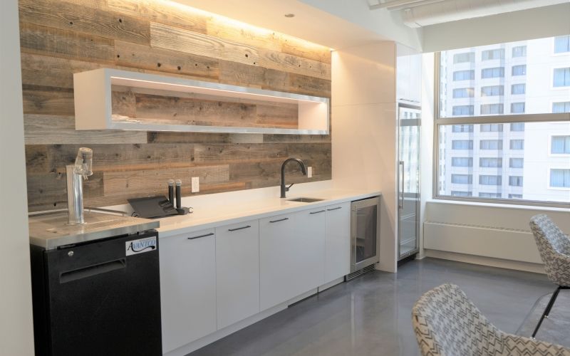 A break room with a sink, fridges and some cabinets.