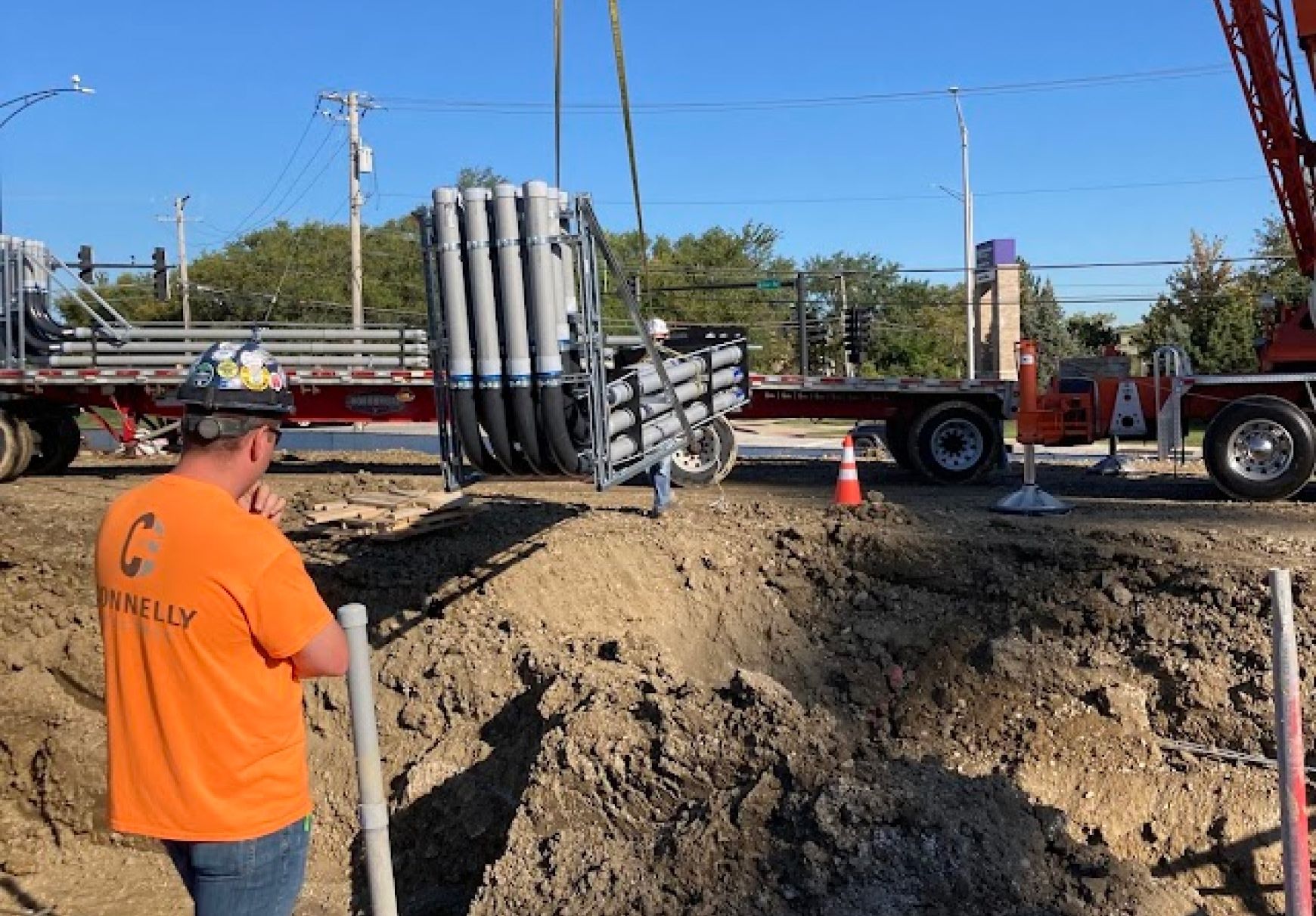 A crane placing prefabricated duct banks underground at an electrical construction site being oversaw by a Connelly Electric project manager.
