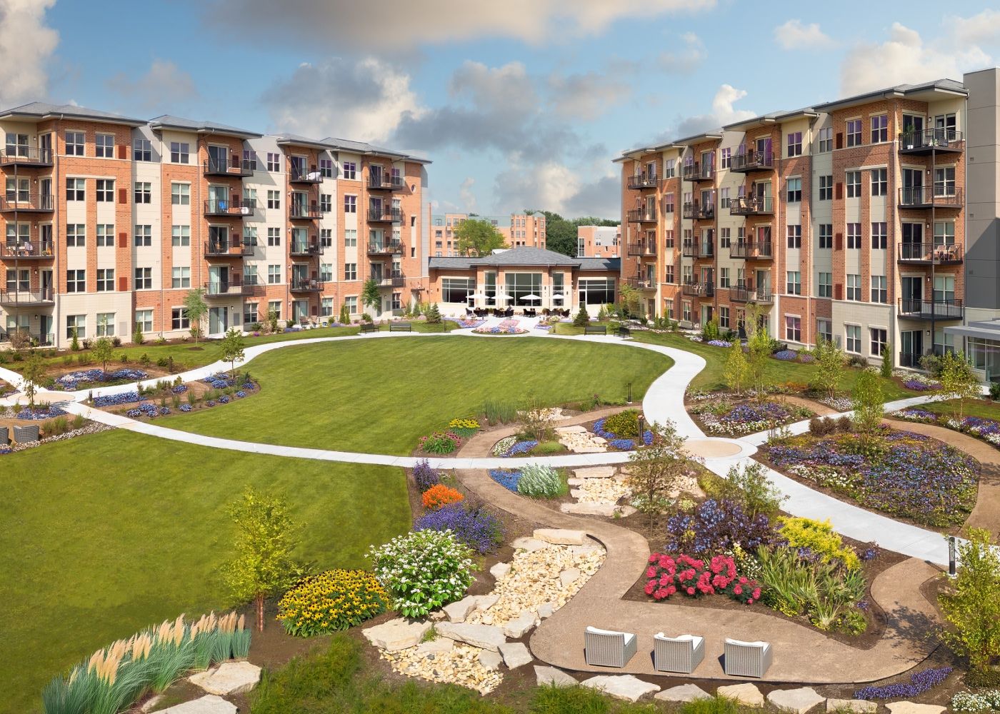 The property across from a small beautiful garden filled with yellow, orange, pink, purple and white flowers.