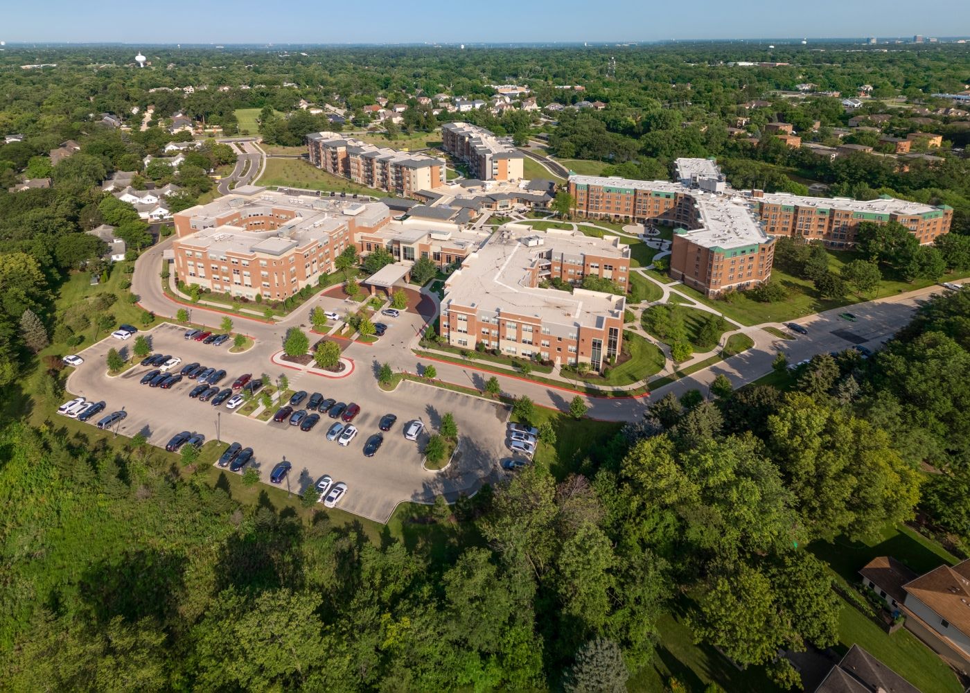 Aerial view of the property, showing a large parking lot with cars and surrounding green fields and trees.
