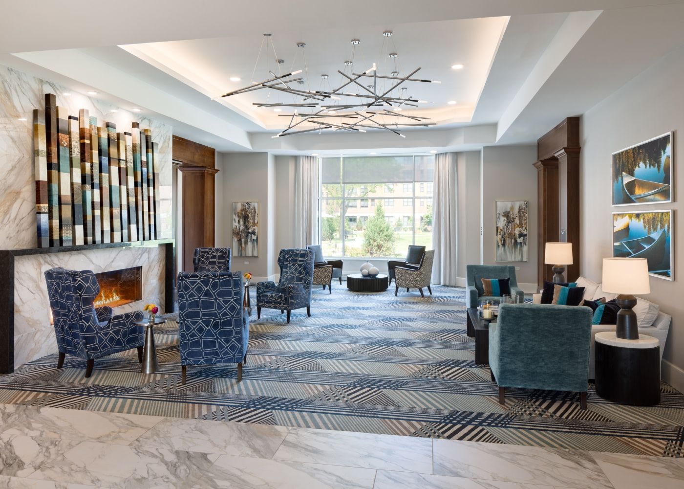 The living room area with comfortable couches and chairs, art on the walls and modern pendant lights.