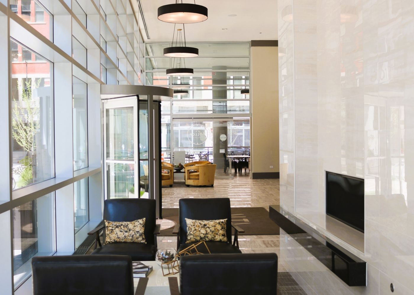 The entrance of Alta Roosevelt with a revolving door, couple chairs and tv.