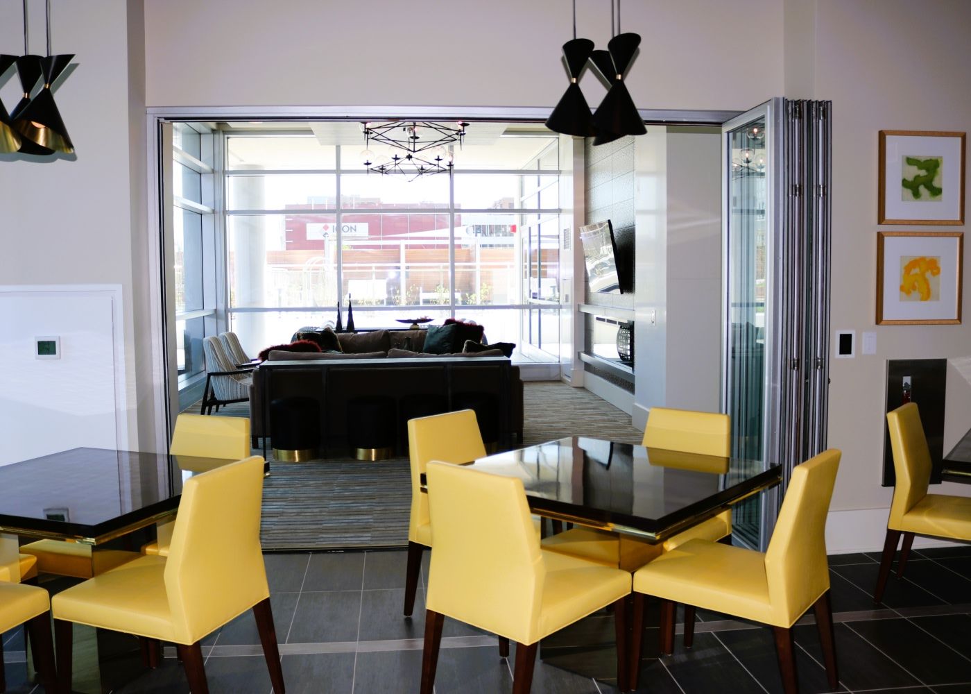 A couple tables and yellow chairs next to a living room.