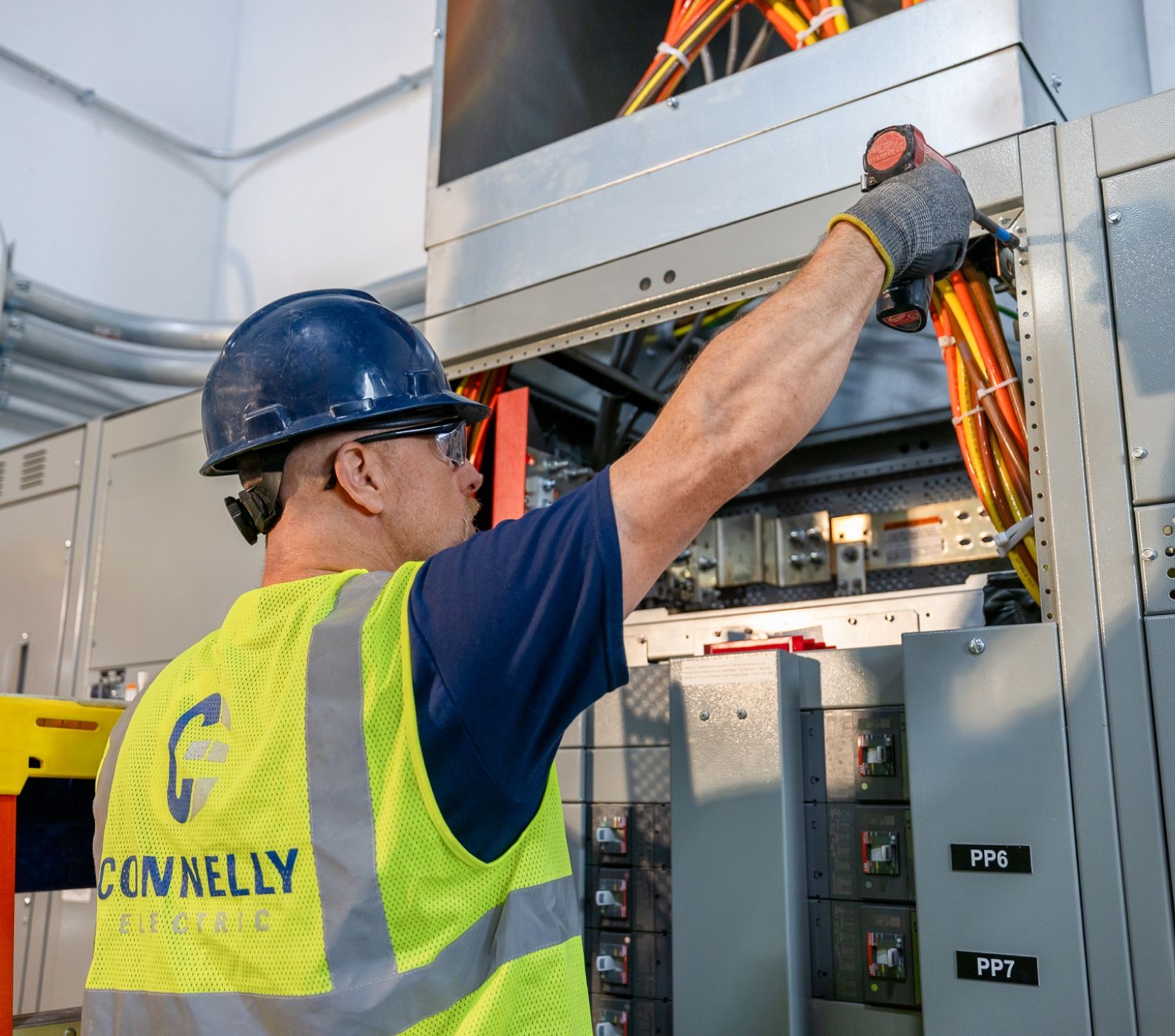 Connelly Electric service technician providing general electric maintenance in a hard hat and safety vest.