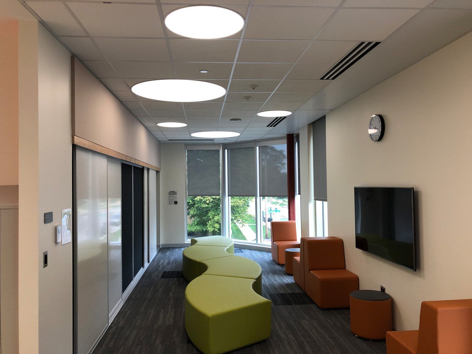 Carpeted hallway of East Prairie with a couple chairs and other colorful seating options.