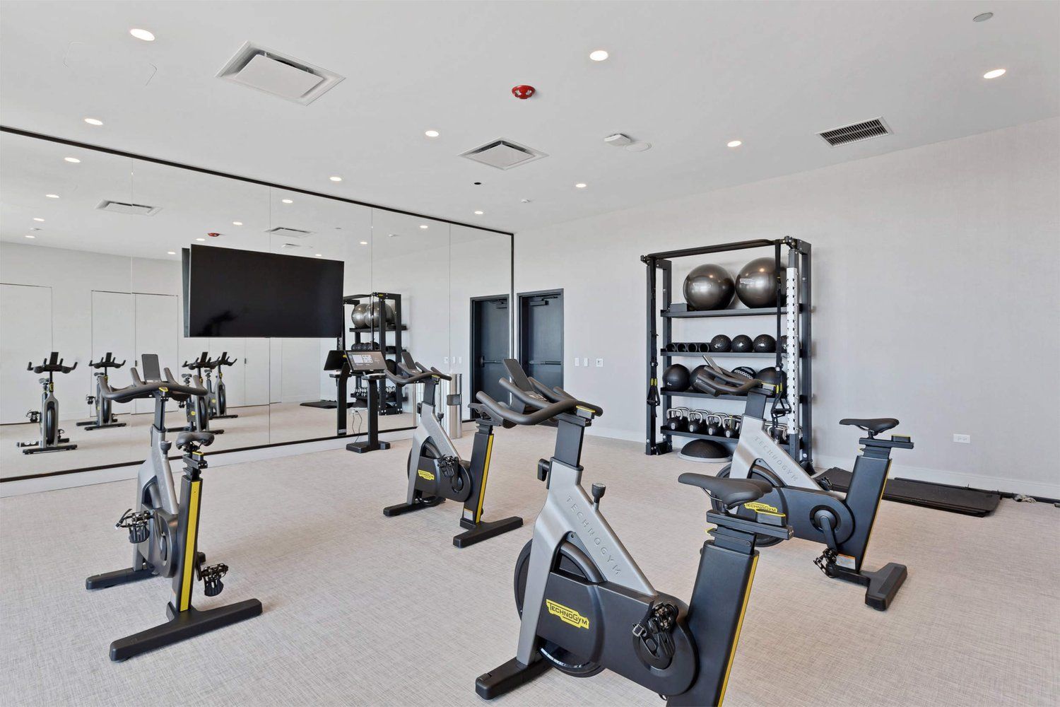 The exercise room with several treadmills and gym equipment.