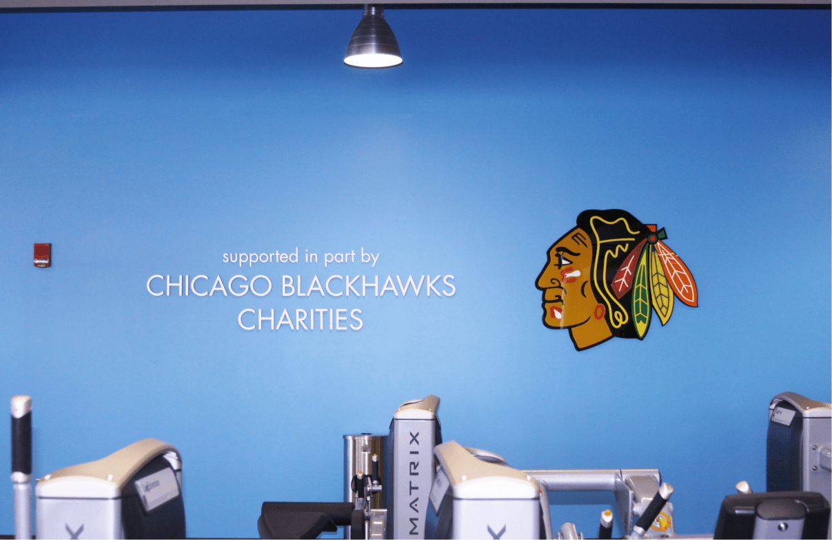 Blue wall next to exercise machines with a Blackhawks logo and the words "Supported in part by Chicago Blackhawks Charities."