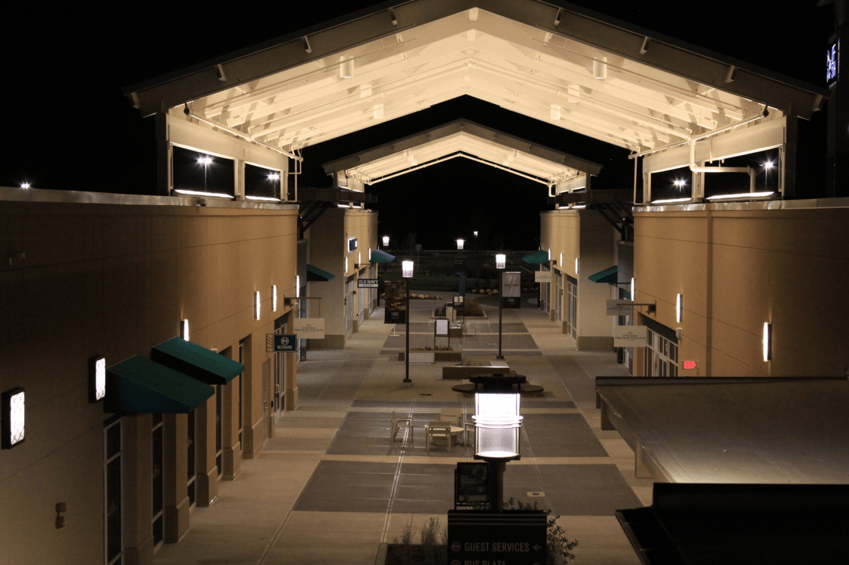 The outdoor Chicago Premium Outlets at night showing decorative wall sconces, decorative pole lights and the main door of several shops.