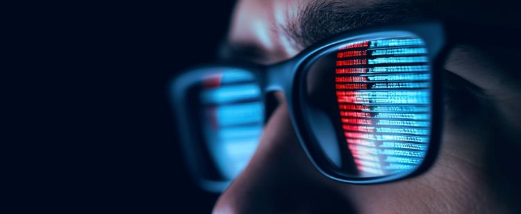 Lines of code reflected in the lens of a pair of sunglasses a person is wearing