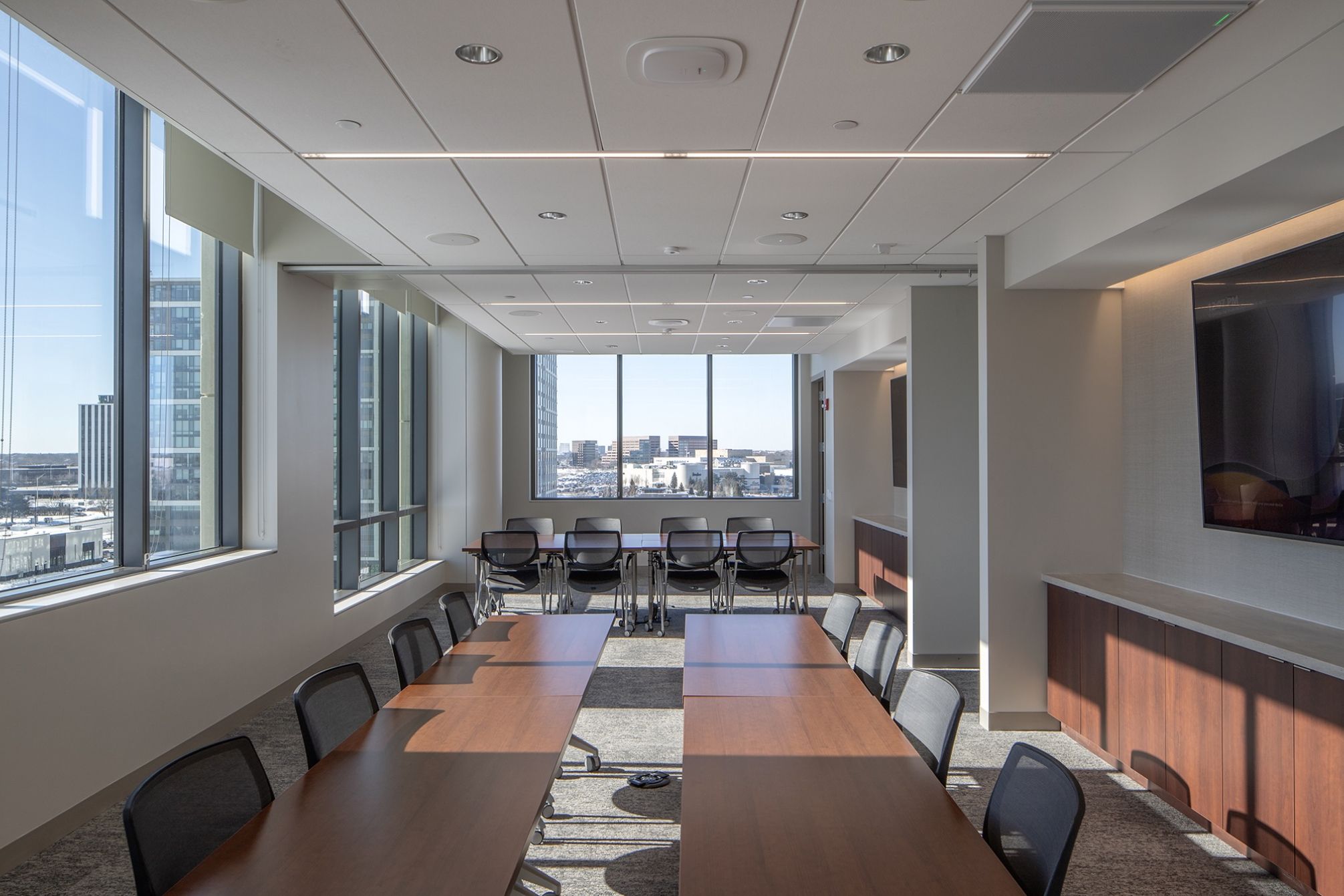 Meeting room with three long tables and chairs all around them.