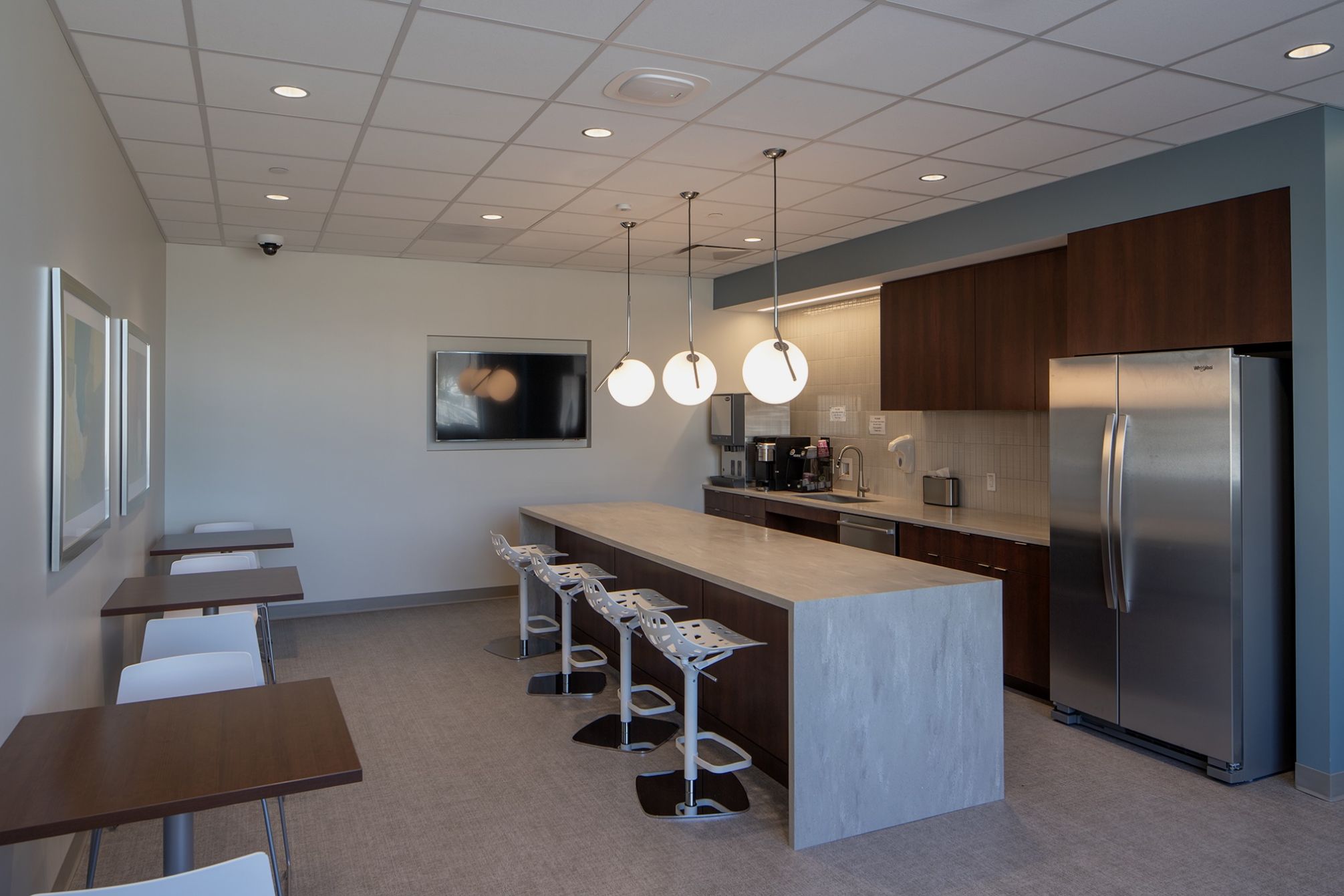 Break room with a fridge, a countertop, chairs and small tables