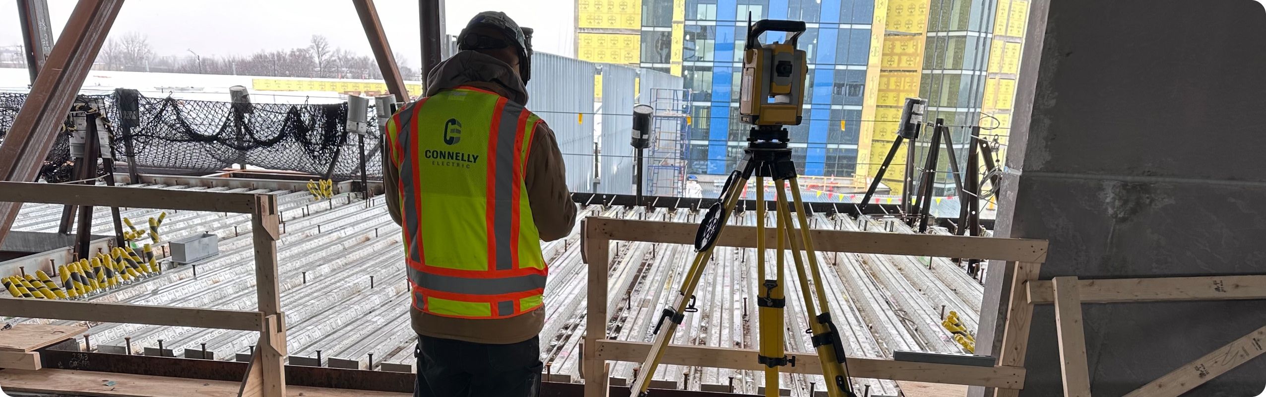 Connelly Electric Technician using a Trimble Total Station at a construction job site.