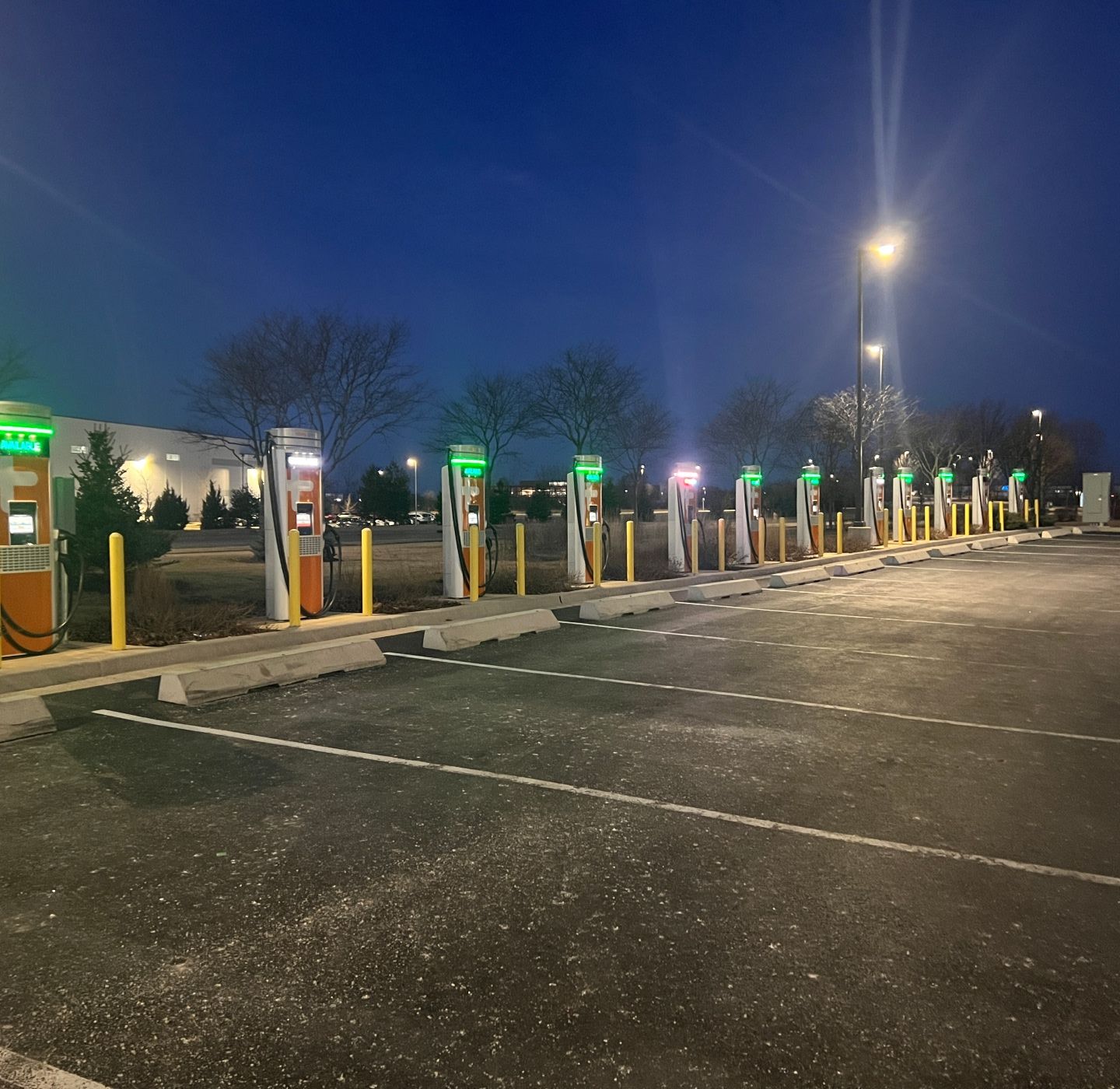 Electric vehicle charging stations in a parking lot at night.