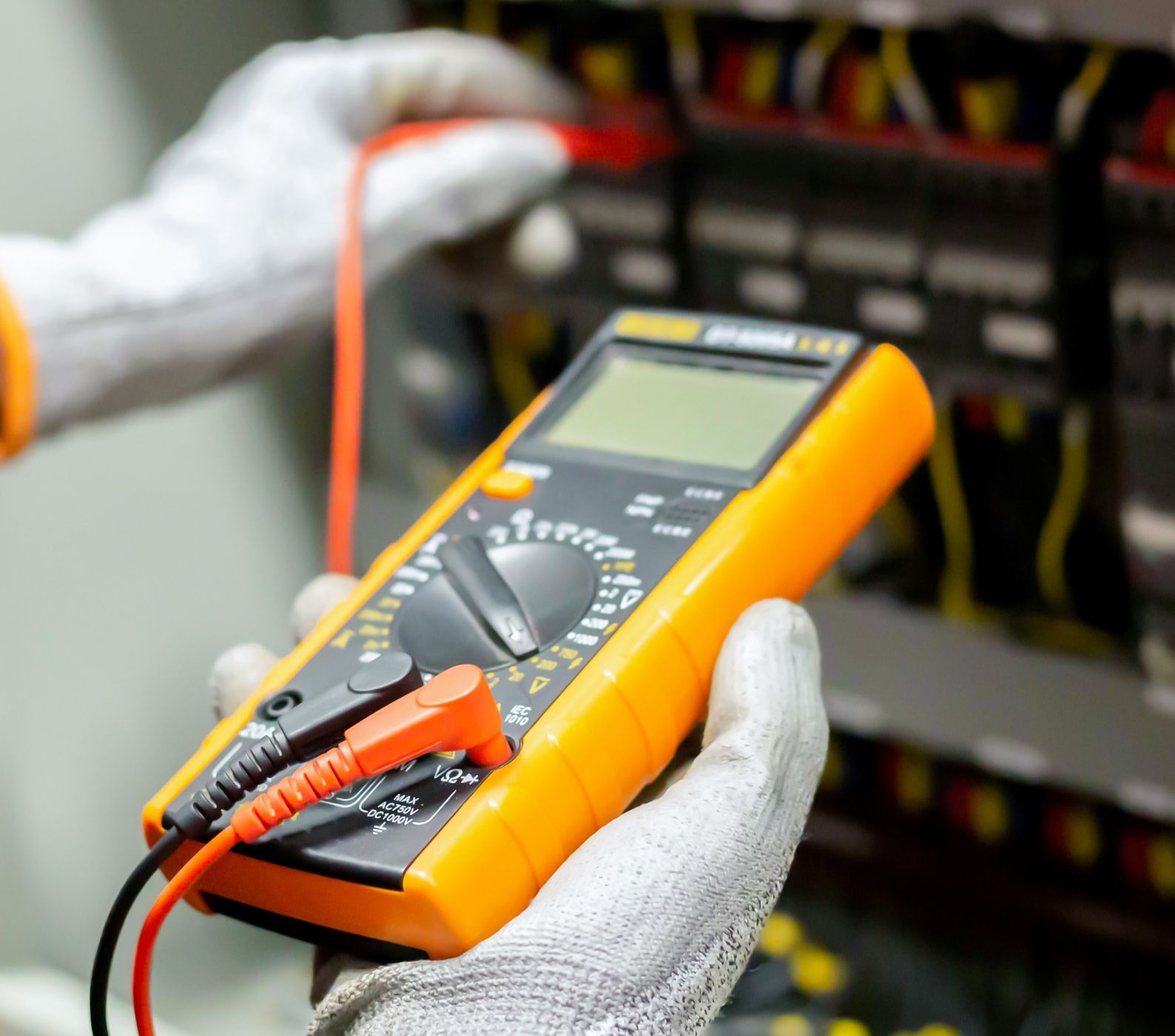 Service technician using a digital multimeter (DMM) to measure and verify voltage. 