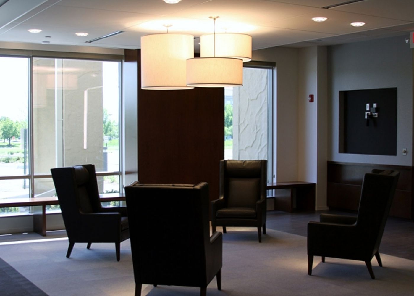 Lobby with four couch armchairs and three pendant lights of different heights in the middle.