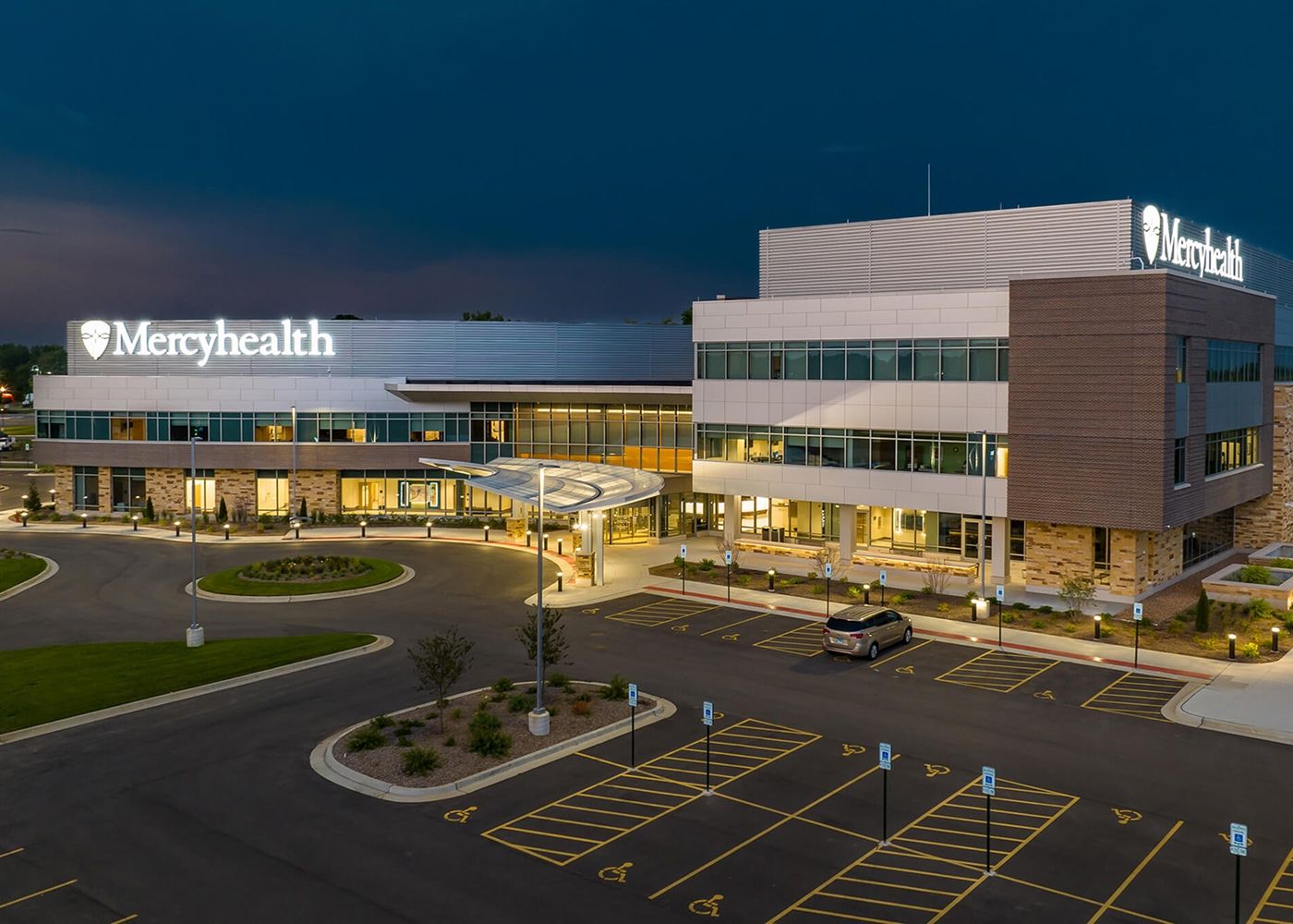 Another view of the exterior of Mercy Health with the inside illuminated.