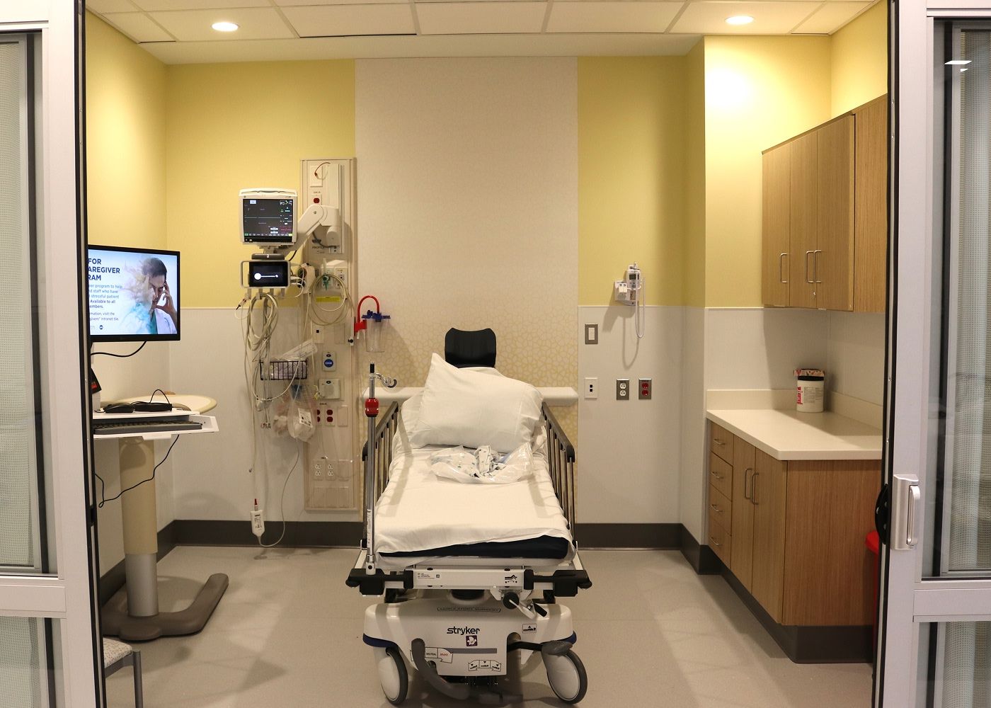 Patient room with an an ambulatory bed, a screen and medical equipment.