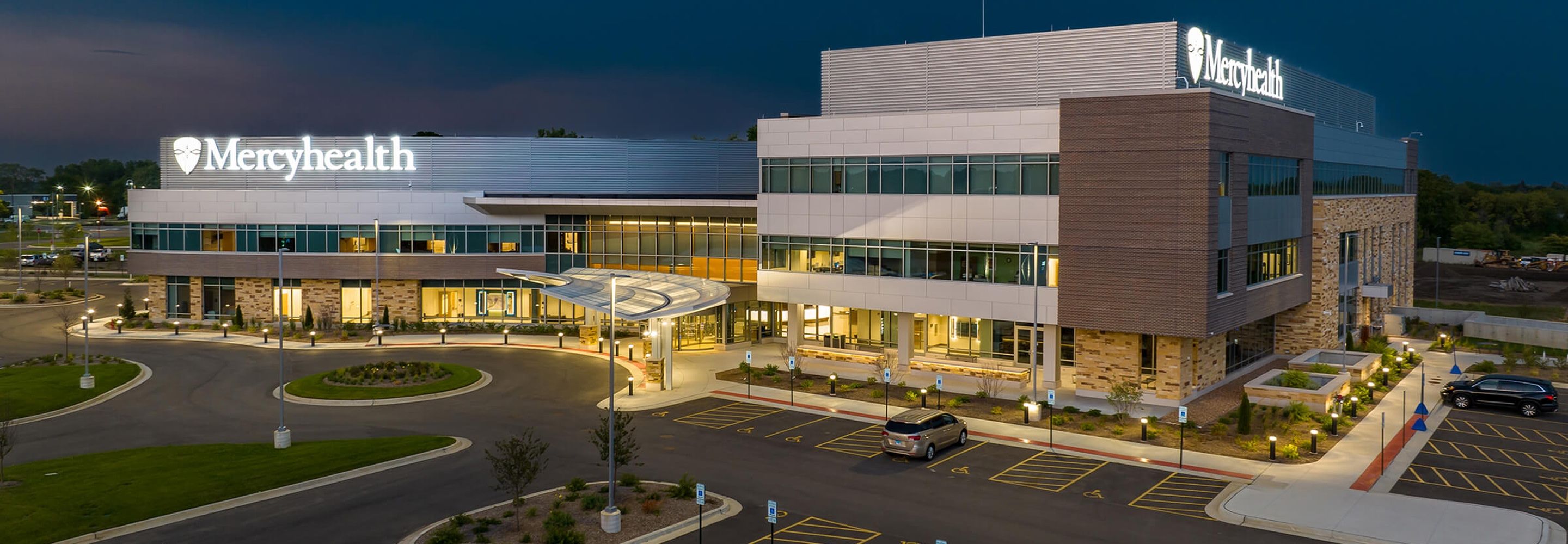 Another view of the exterior of Mercy Health with the inside illuminated.