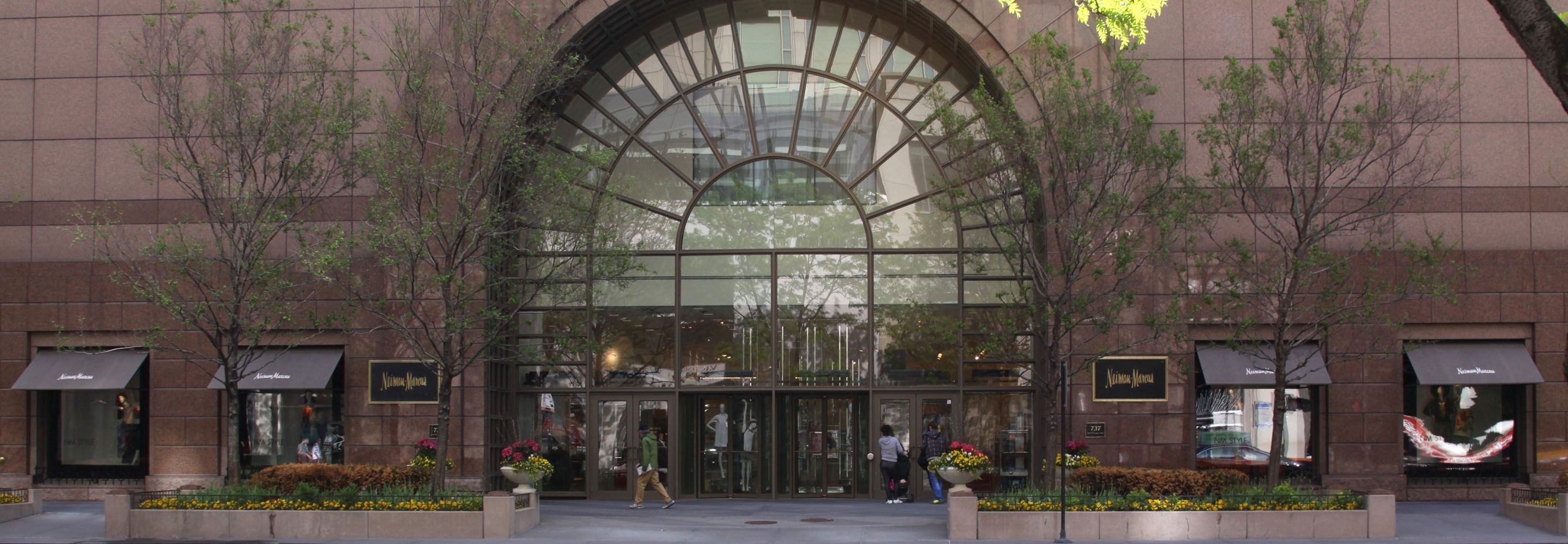 The exterior facade of Neiman Marcus showing a large rounded glass entrance.