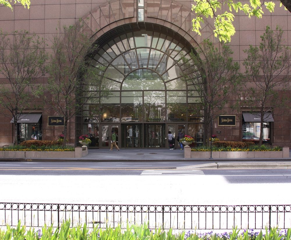 The exterior facade of Neiman Marcus showing a large rounded glass entrance.
