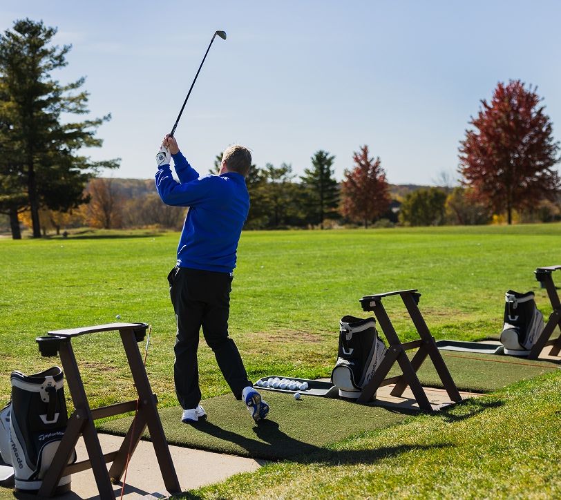 man teeing off at a driving range