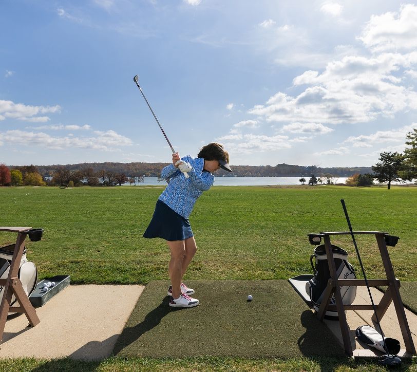 woman teeing off at a driving range