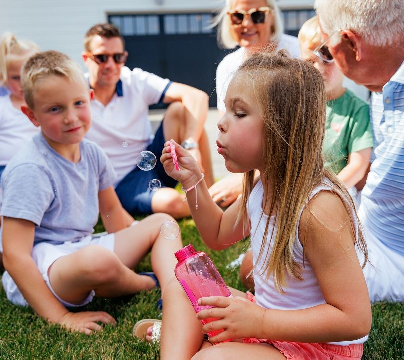 kids blowing bubbles outside with their family