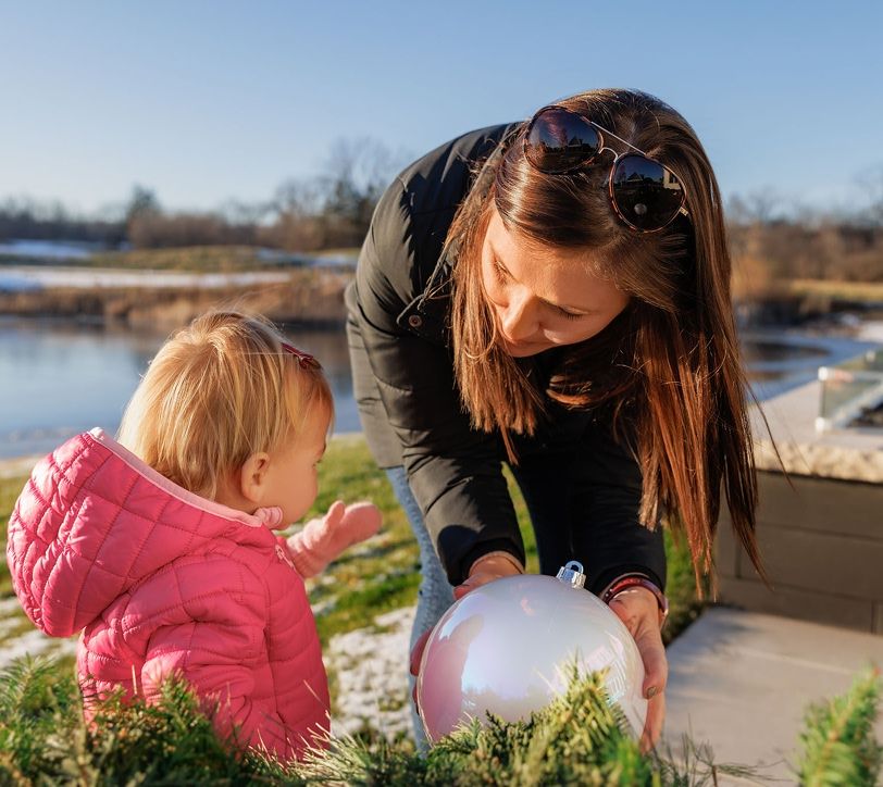 mom and toddler daughter playing with a ball outside