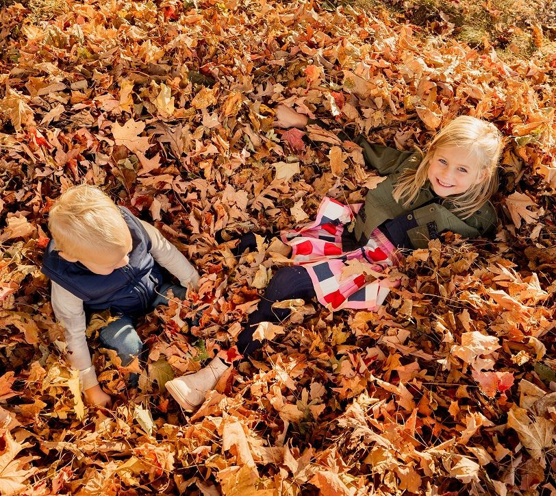 siblings playing in a pile of leaves