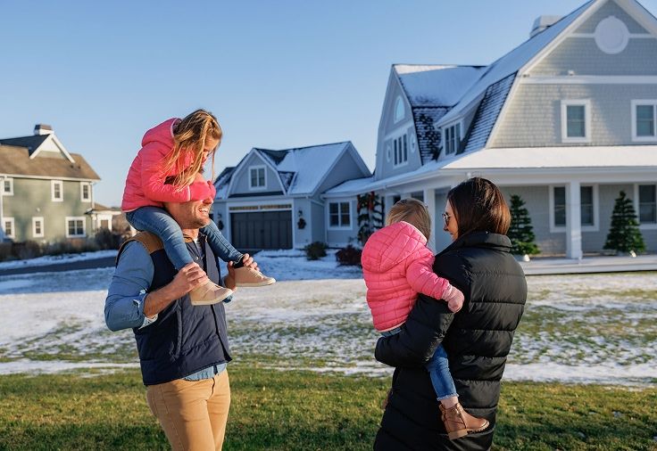 Family playing outside their home in a large field