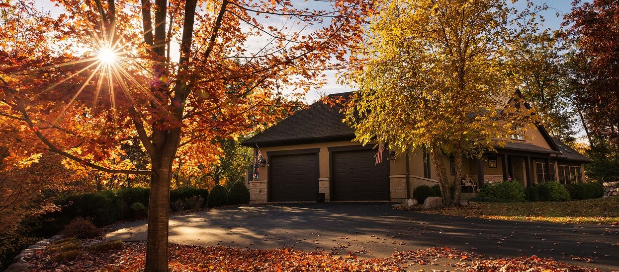 Home with two car garage surrounded by yellow and orange trees during autumn