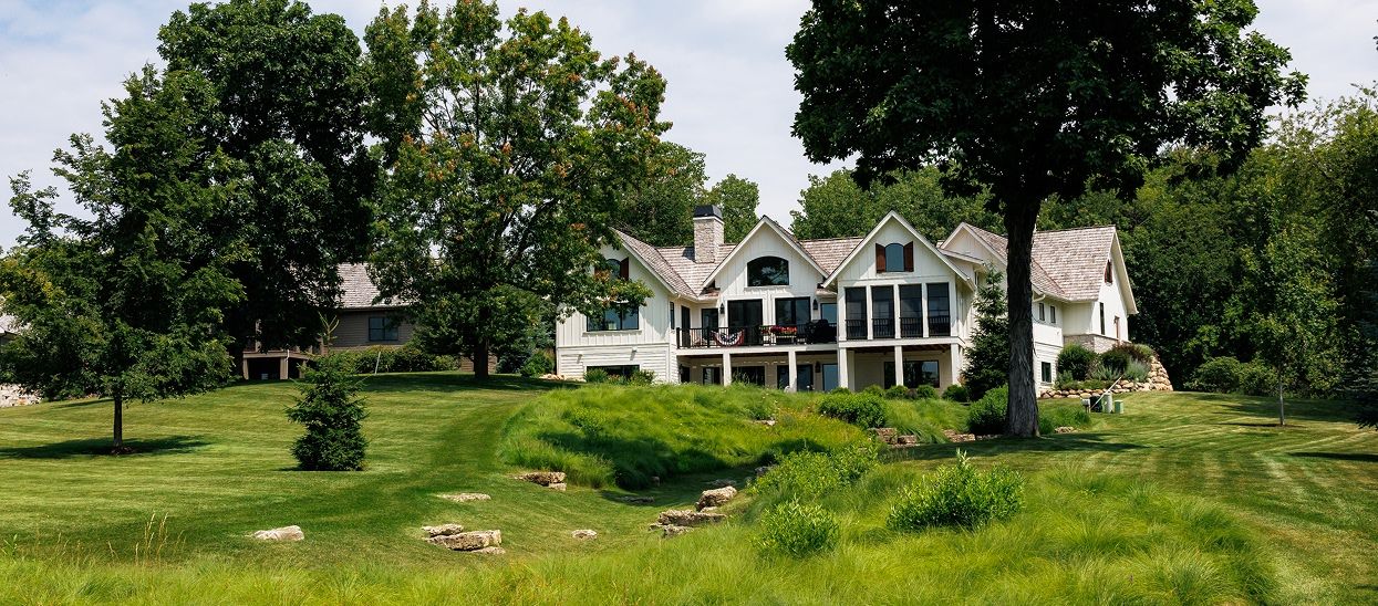 White traditional home decorated for 4th of July overlooking green fields