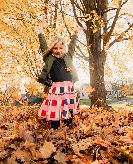 Child playing in leaves outside during Autumn