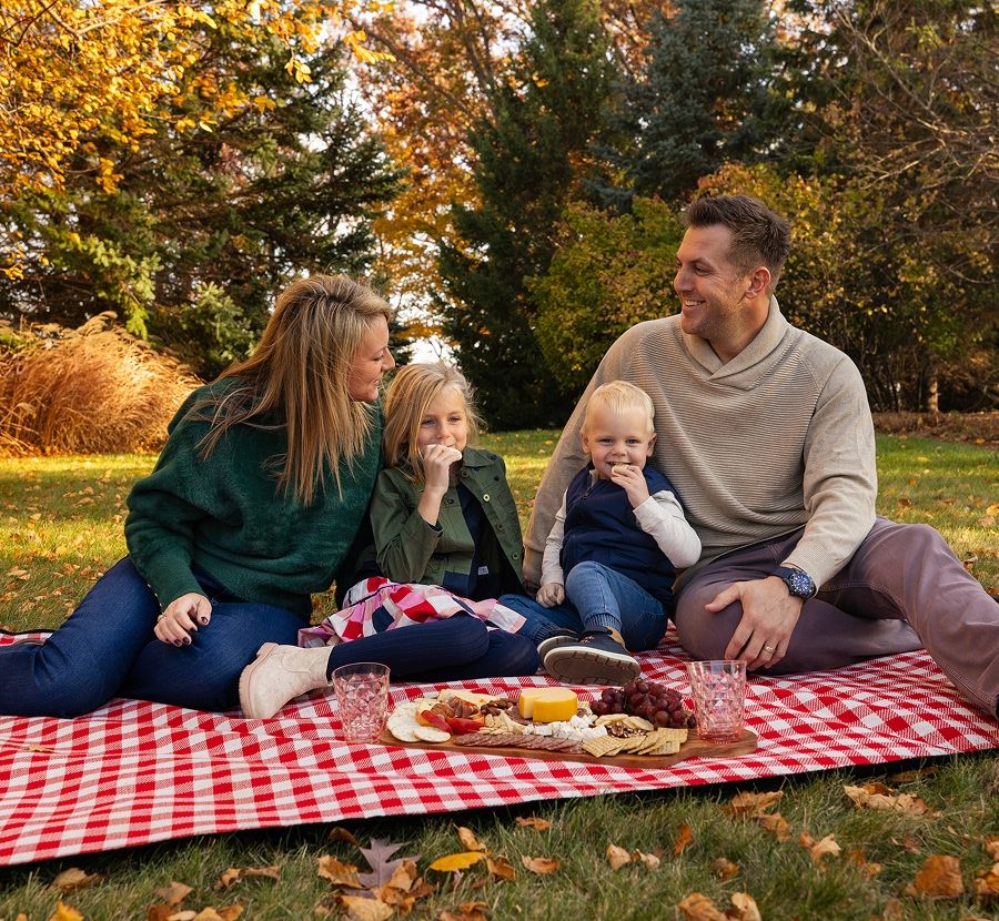 Mom, dad, and their two kids having a picnic outside during autumn