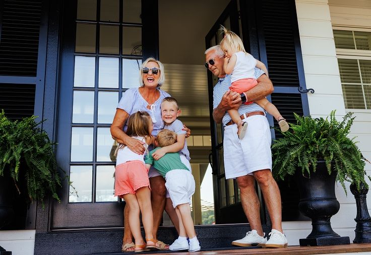 Grandparents playing with four grandchildren outside their home on the front steps