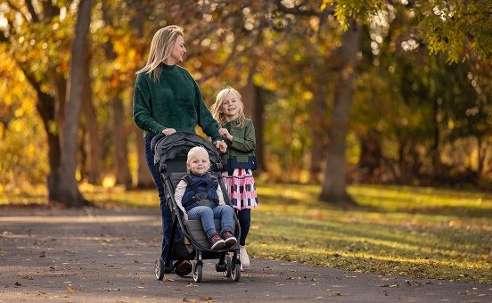 Mom with two daughters walking along a trail outside during autumn