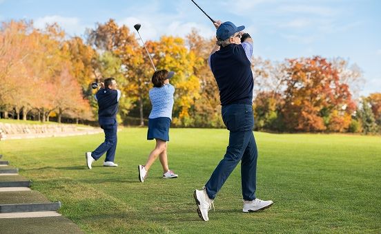 three people teeing off at a driving range