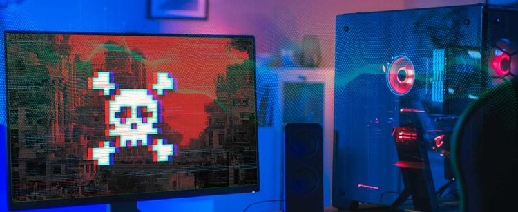 A computer monitor showing a skull and cross bones on a red background, presumably hacked