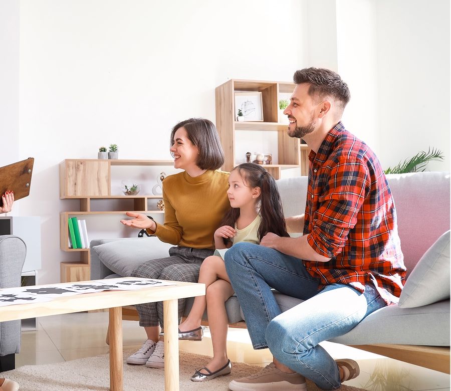 mom and dad sit with their young daughter in a family therapy session