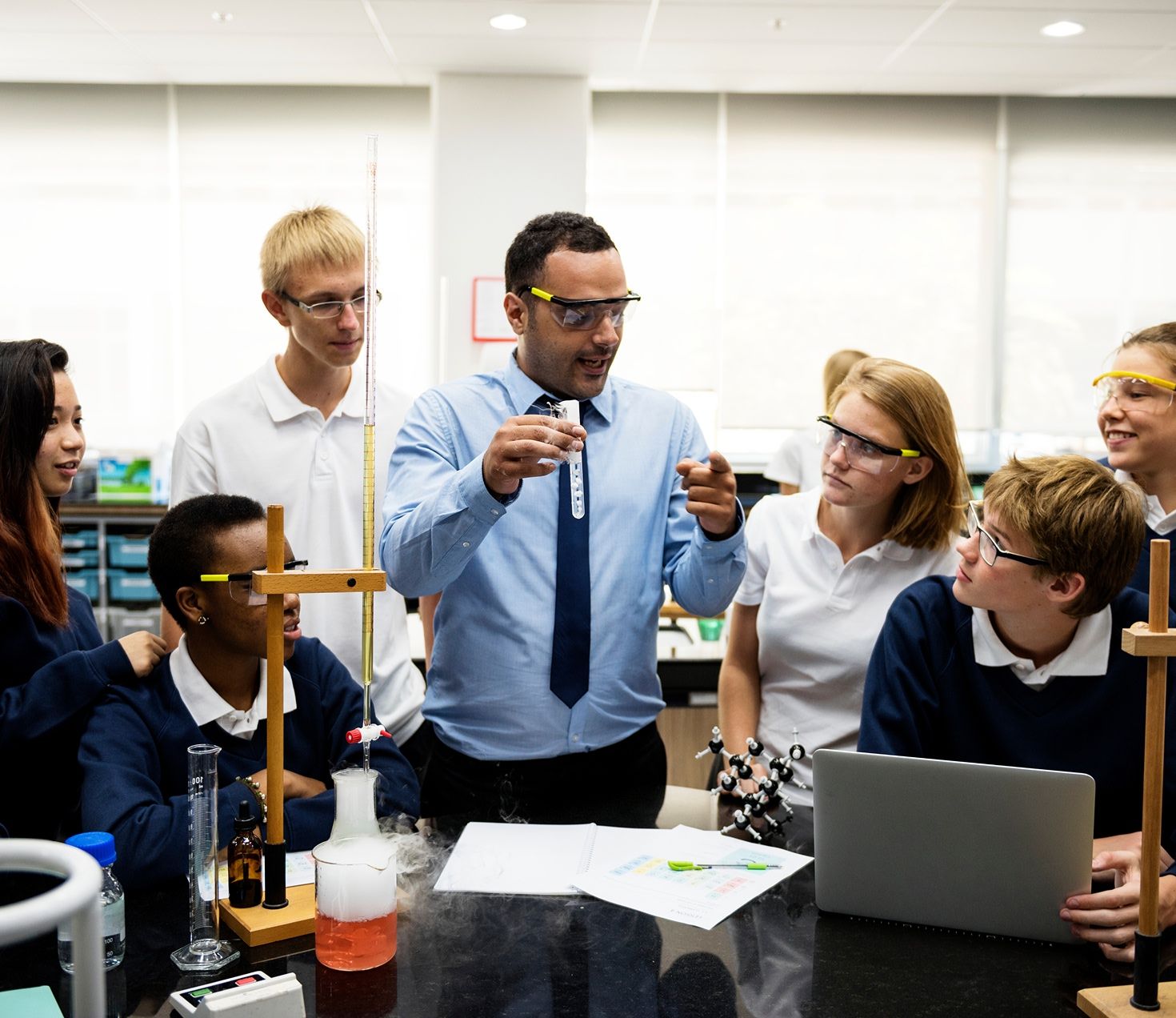 science teacher demonstrates a chemistry project to classroom of students