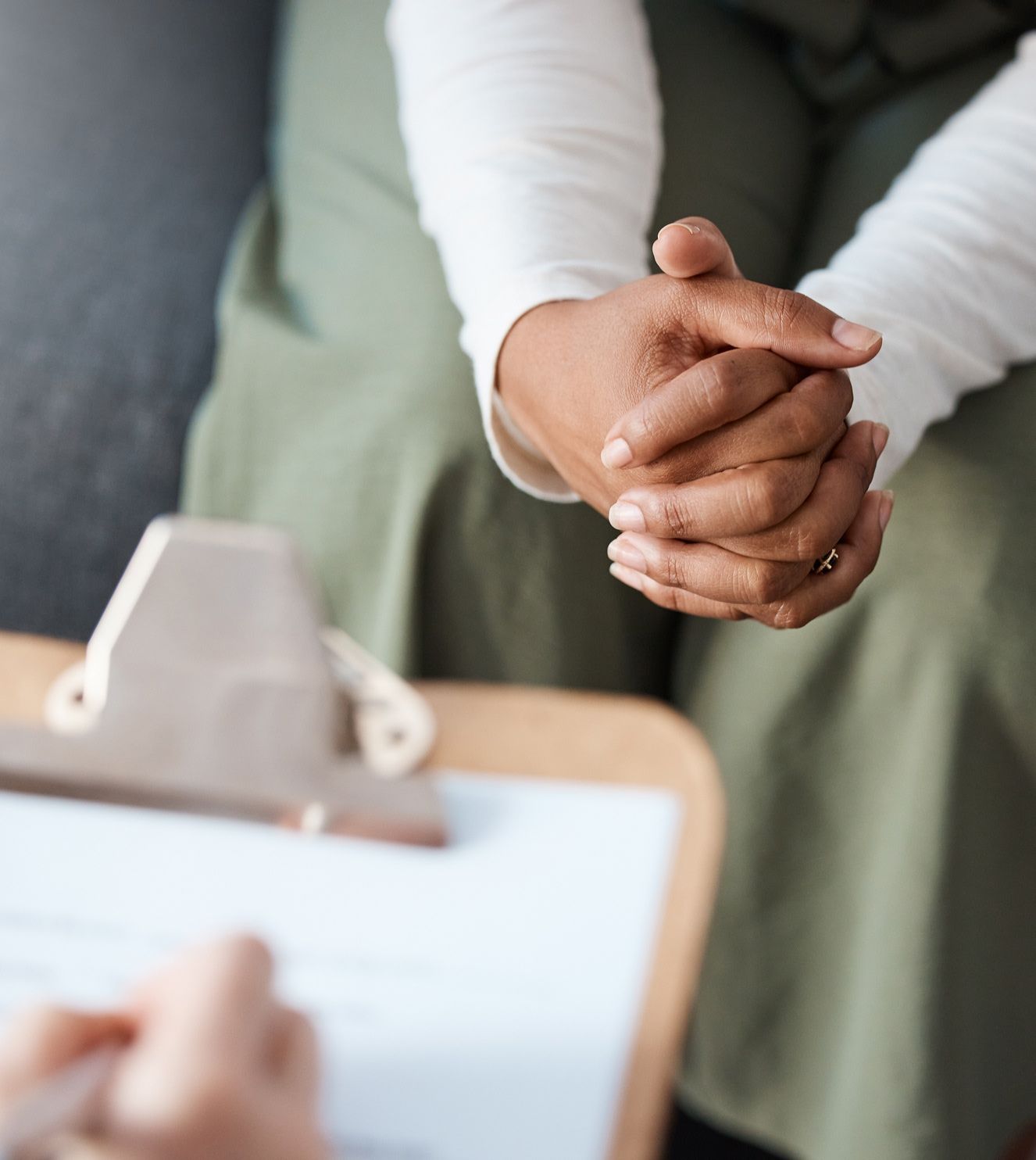person sitting with their hands folded across someone with a clipboard