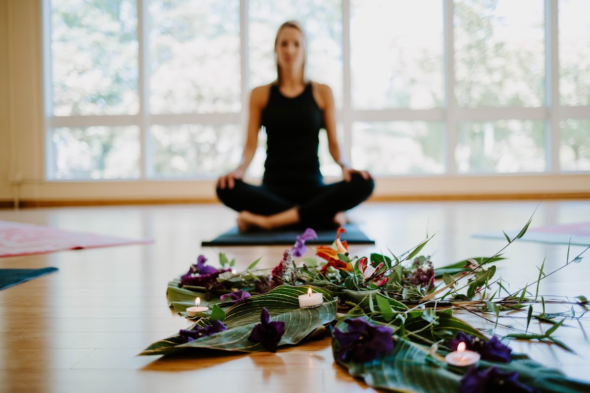 Yoga practitioner meditating behind flowers and candles at Common People Yoga