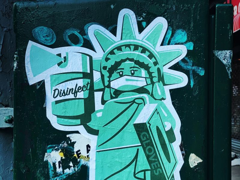 Graffiti image shows the Statue of Liberty with disinfectant and gloves in cartoon image. Credit: Jon Tyson, Unsplash